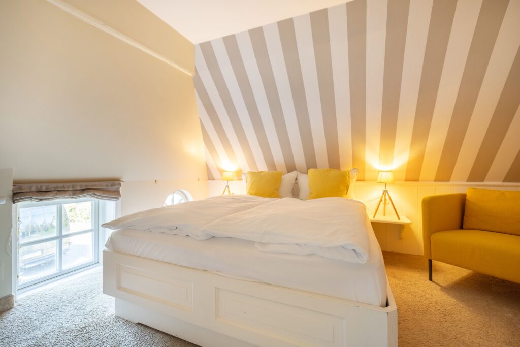 Doppelbett mit gelben Kissen und Sessel in Ferienwohnung in Keitum