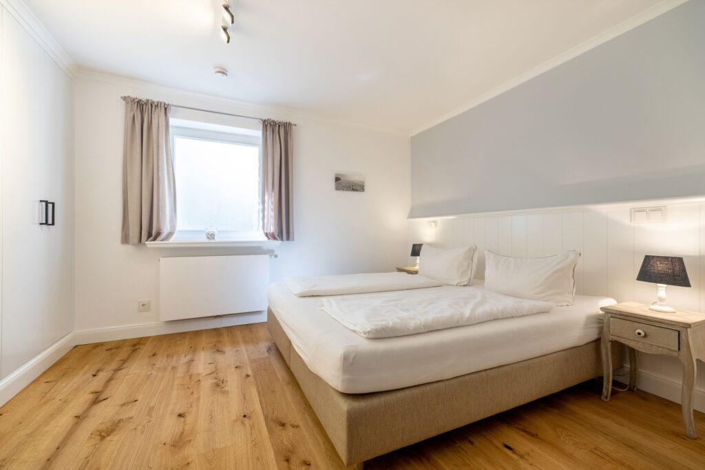 Doppelbett mit Tischlampe in Ferienwohnung in Keitum