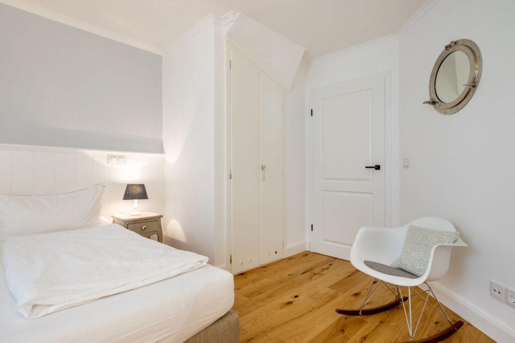 Doppelbett mit Stuhl und Spiegel in Ferienwohnung in Keitum