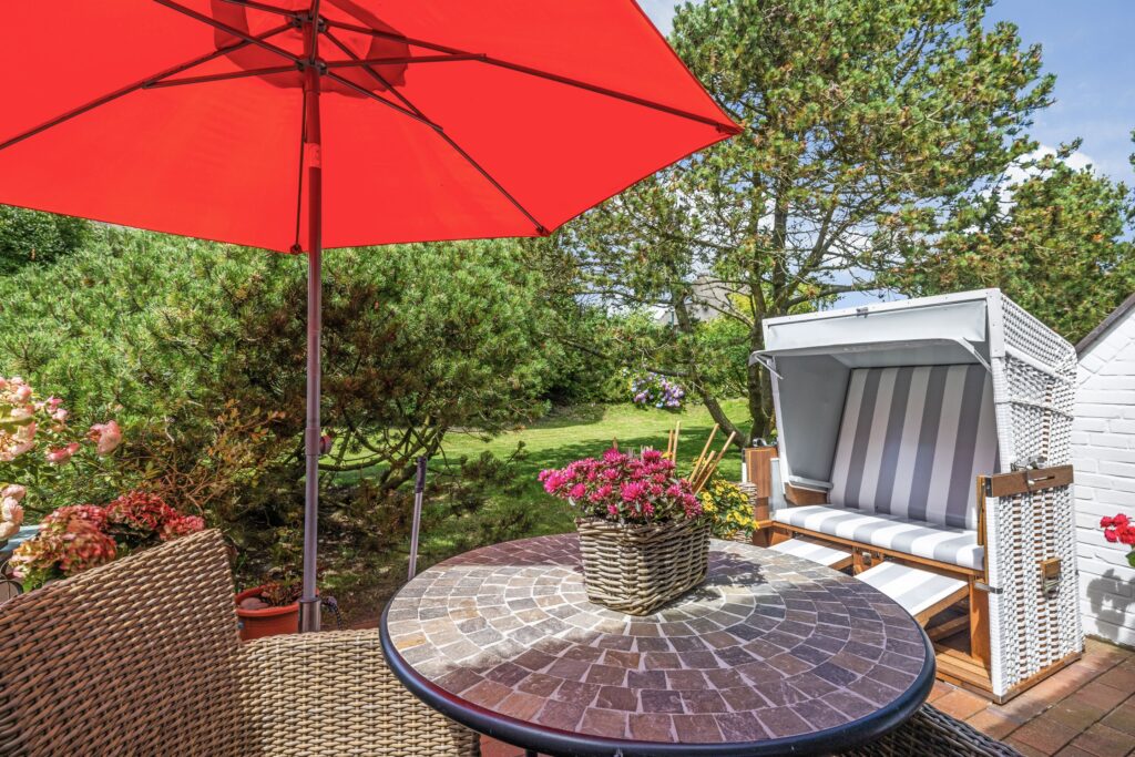 Sonnenschirm, kleiner Tisch und Strandkorb in Ferienwohnung auf Sylt