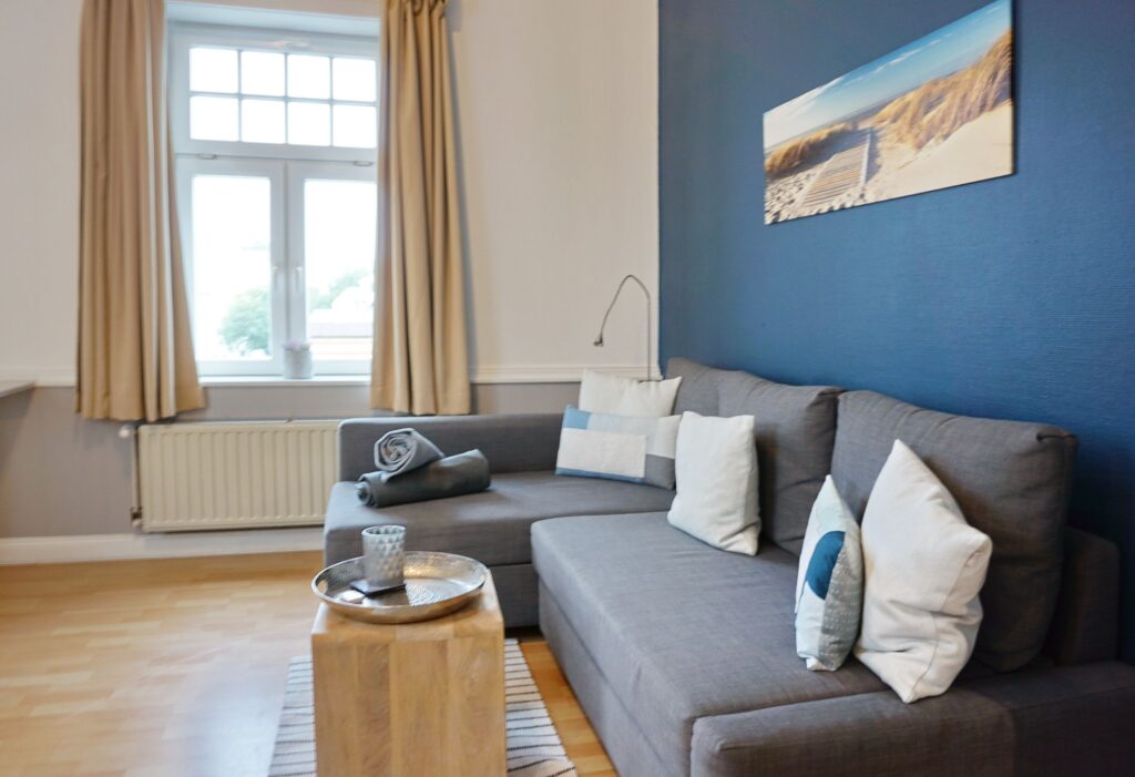 graues Sofa und blaue Wand in Ferienwohnung auf Sylt