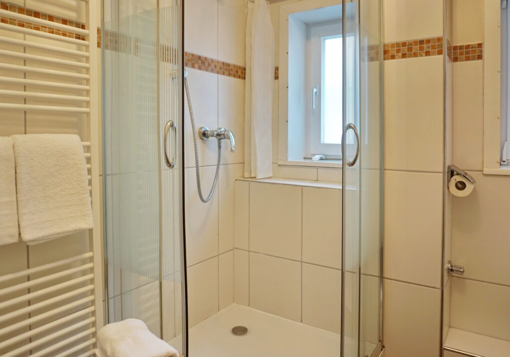 Badezimmer mit Dusche und Fliesen in Ferienwohnung auf Sylt